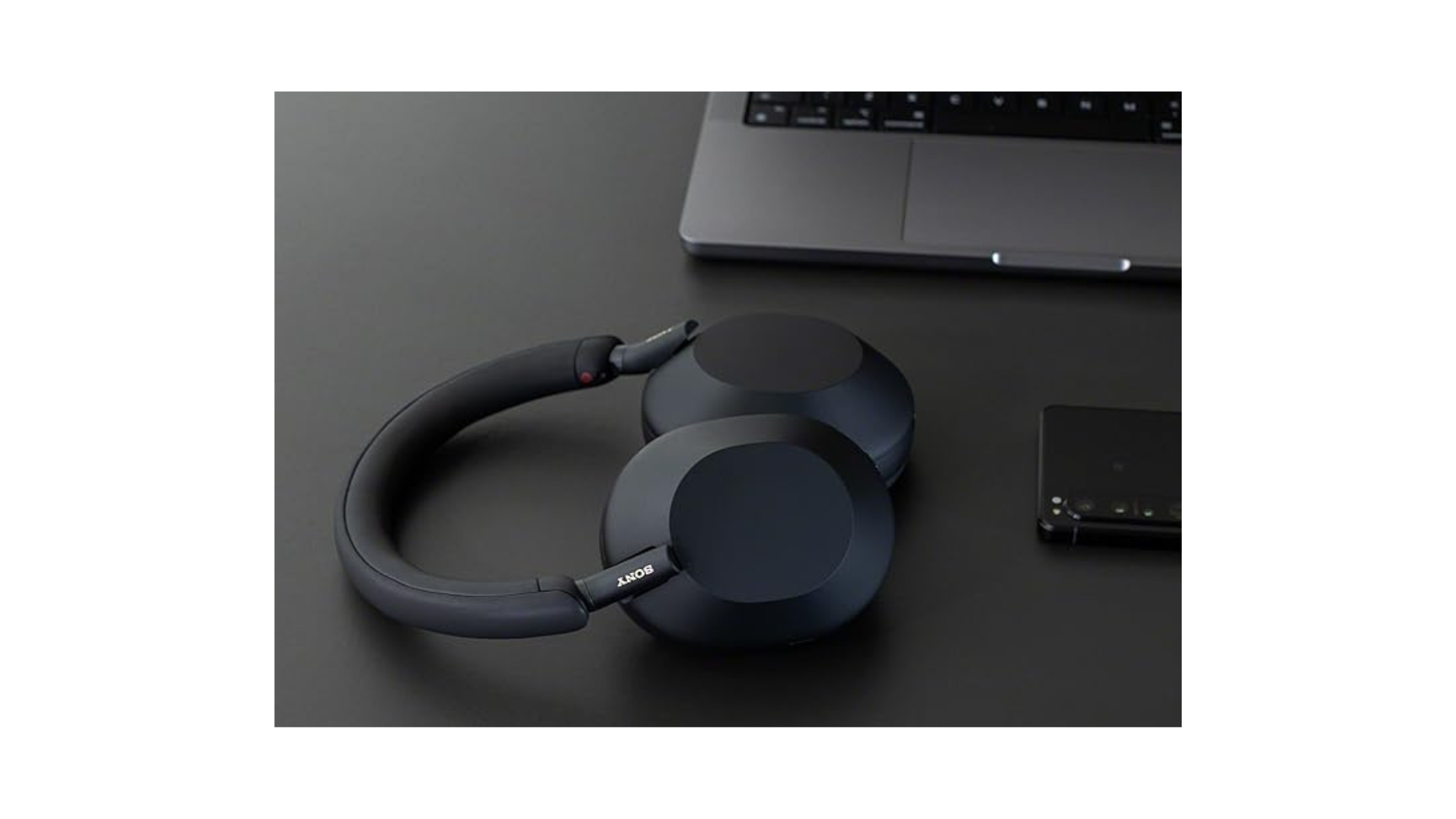 headset Sony WH-1000XM5 sobre a mesa juntamente com outros dispositivos